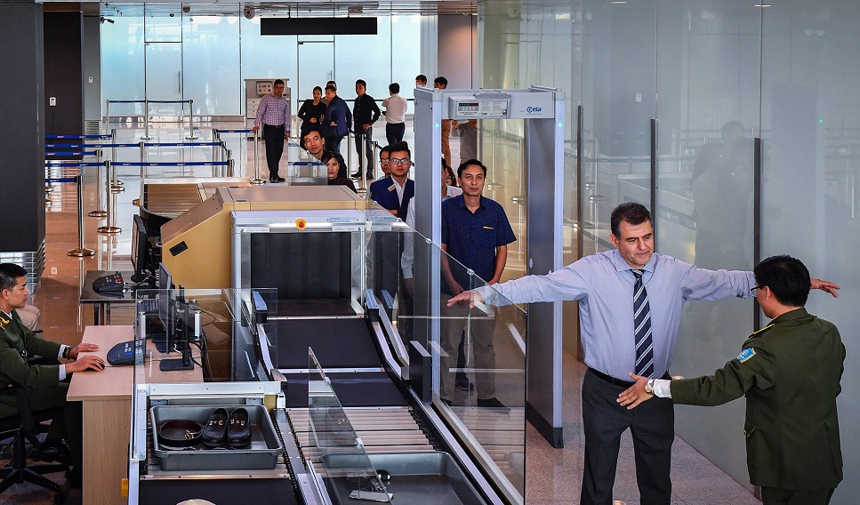 Người và hành lý xách tay sẽ được nhân viên an ninh kiểm tra qua cổng bằng máy quét. 